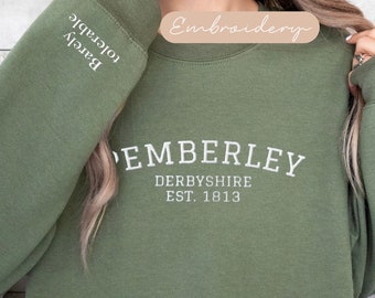 Puede incluir: Una sudadera verde con bordado blanco que dice "Pemberley, Derbyshire Est. 1813". La manga izquierda tiene las palabras "Barley Tolerable" bordadas en blanco.