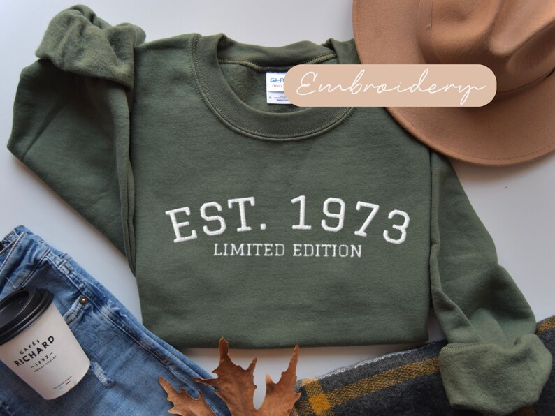 May include: A green sweatshirt with white embroidered text that reads "EST. 1973 LIMITED EDITION".