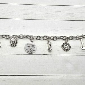 Può includere: Braccialetto d'argento con ciondoli a tema pompiere, tra cui un camion dei pompieri, un'ascia, un cappello da pompiere e un ciondolo con il testo "Some Never Meet Their Hero, But I Raised Mine".