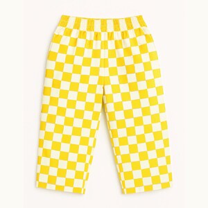 May include: Yellow and white checkered pants with an elastic waistband. The pants have a cropped length and a bold, eye-catching pattern. The checkered design is made up of evenly sized squares.