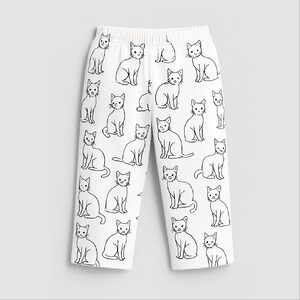 May include: White trousers featuring a repeating black outline cat design. The cats are depicted in different poses, such as sitting and standing. The trousers have an elasticated waistband.