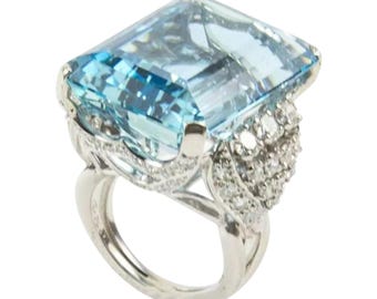 May include: A large, rectangular aquamarine gemstone ring. The light blue gemstone is set in a silver band with intricate detailing and smaller, clear gemstones. The ring has a classic, elegant design.