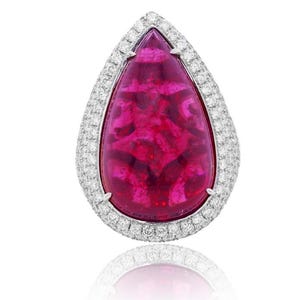 May include: A pear-shaped pink gemstone ring with a diamond halo setting. The gemstone has a carved design and is set in a white metal band.