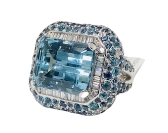 May include: A silver ring with a large, rectangular aquamarine gemstone surrounded by smaller blue and white gemstones.
