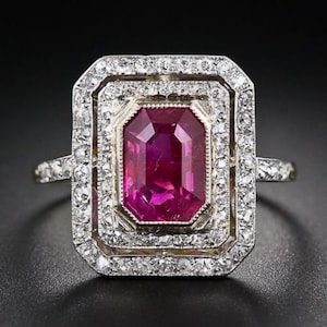 May include: A vintage ring with a large, vibrant pink ruby surrounded by a double halo of sparkling diamonds.