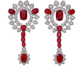 Puede incluir: Un par de pendientes elegantes con un diseño floral. Cada pendiente presenta un rubí ovalado central rodeado por un halo de diamantes. Rubíes y diamantes adicionales están dispuestos en cascada, creando un accesorio lujoso y llamativo.