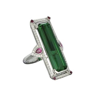Può includere: Un anello d'argento con una grande pietra preziosa verde circondata da diamanti e pietre preziose rosa più piccole.