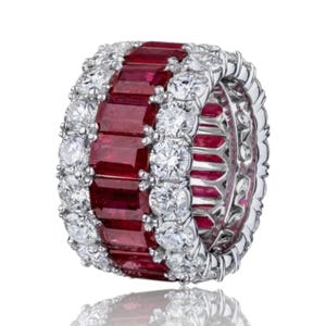 May include: A luxurious ring featuring a band of rectangular, deep red gemstones, flanked by rows of sparkling, round, white gemstones. The ring has a polished, metallic setting, reflecting light and creating a dazzling display of color and brilliance.