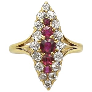 May include: A gold ring with a marquise-shaped setting featuring a row of five ruby stones surrounded by a halo of diamonds.