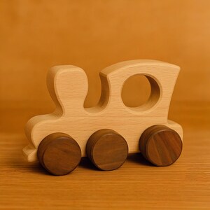 May include: A wooden toy train with brown wheels. The train is made of light wood and has a simple design.
