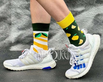May include: A person wearing a pair of white sneakers with blue and red accents. The person is wearing a pair of socks with a lemon and green leaf pattern. The person is wearing blue denim shorts and a yellow shirt.