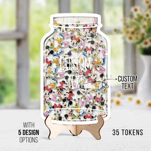 Pode incluir: Um expositor de madeira em forma de frasco com uma borda branca, preenchido com gráficos de personagens de desenhos animados. O frasco tem as palavras "CUSTOM TEXT" e "35 TOKENS" impressas. O expositor é suportado por um suporte de madeira.