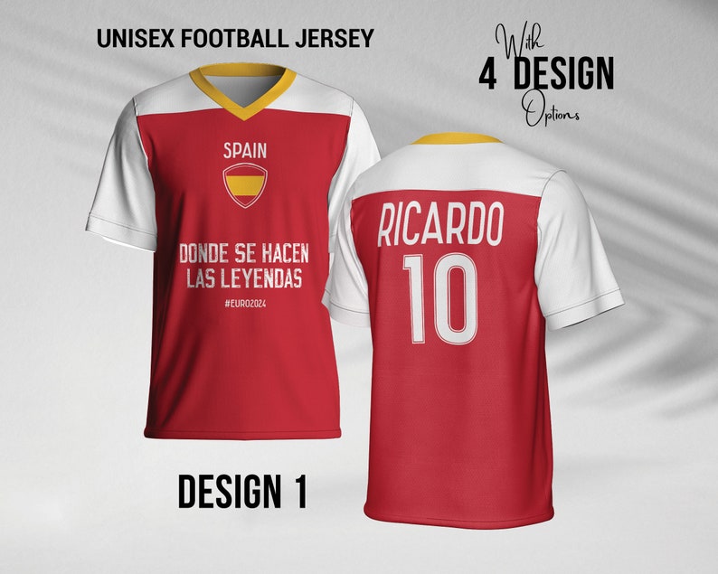 May include: Red and white soccer jersey with the text "SPAIN" and the Spanish flag on the front. The back of the jersey has the text "RICARDO" and the number "10" in white. The jersey has a yellow trim around the neck and sleeves.