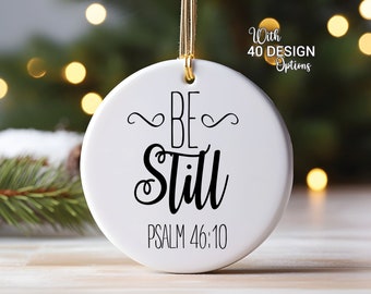 May include: White ceramic Christmas ornament with black calligraphy that reads "Be Still" and "Psalm 46:10".