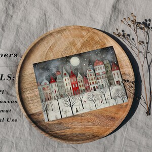 May include: A digital illustration of a snowy town at night with a full moon and stars in the sky. The houses are painted in shades of red, white, and gray. The illustration is on a wooden surface.
