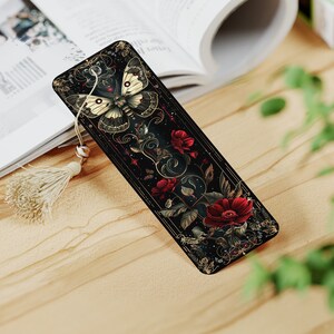May include: A black bookmark with a gold and white butterfly design and red flowers. The bookmark has a tassel.