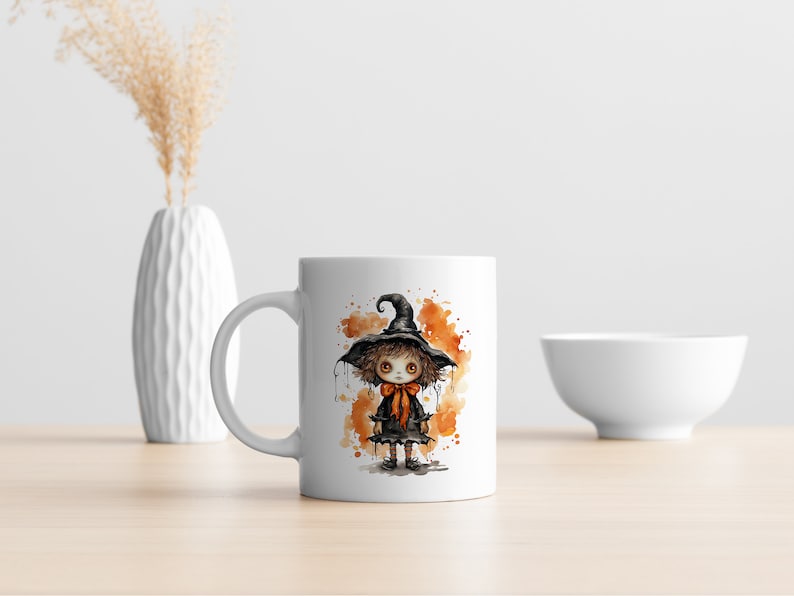 May include: White ceramic mug with a watercolor illustration of a young witch wearing a black hat and orange bow. The witch is standing on a background of orange and brown watercolor splatters.