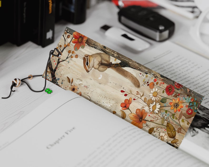 May include: A bookmark featuring a whimsical illustration of a squirrel holding a flower, surrounded by colorful flowers and leaves on a beige background.