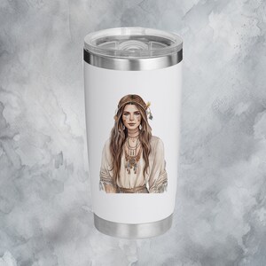 Puede incluir: Un vaso de acero inoxidable blanco con una ilustraci&oacute;n colorida de una mujer con cabello largo y casta&ntilde;o que lleva un vestido blanco y joyas. La mujer lleva una diadema y plumas en el cabello.