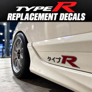 Op de afbeelding: Een wit zijpaneel van een auto met een Type R-sticker met Japanse tekens en een rode letter R. De sticker is geplaatst boven de zijskirt, bij een zilverkleurig meerspaaks wiel met een zwarte band. De tekst Type R Replacement Decals is zichtbaar.