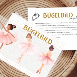 Könnte beinhalten: Ein Blatt mit drei Illustrationen von Ballerinas in rosa Tutus, mit dem Wort "BÜGELBILD" in goldfarbenen Buchstaben. Eine separate Karte mit deutschen Anweisungen ist ebenfalls sichtbar.