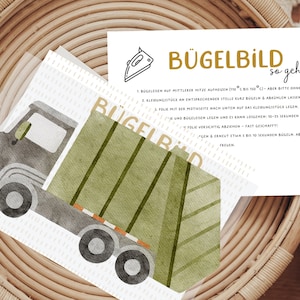 Könnte beinhalten: Ein grüner und grauer illustrierter Müllwagen Bügelbild mit Anweisungen zum Aufbügeln. Die Anweisungen sind in Deutsch und beinhalten den Text "Bügelbild so geht's".