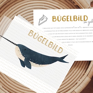 Könnte beinhalten: Eine weiße Karte mit einer Narwal-Illustration und Anweisungen zum Aufbügeln eines Transfers. Die Karte lautet "Bügelbild so geht's" und enthält Schritte zum Aufbügeln des Transfers.
