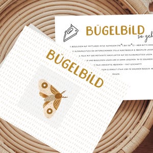 Könnte beinhalten: Anleitung zum Aufbügeln eines Bügelbildes auf Stoff. Die Anleitung ist in deutscher Sprache verfasst und enthält ein Bild eines Bügeleisens und eines Schmetterlings.