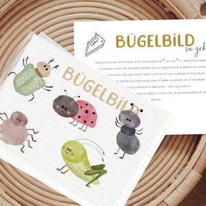 Könnte beinhalten: Ein weißes Bügelbild mit Aquarellillustrationen verschiedener Insekten, darunter ein Marienkäfer und eine Ameise. Eine Karte mit deutscher Anleitung ist ebenfalls vorhanden. Die Artikel werden auf einem geflochtenen Korb präsentiert.