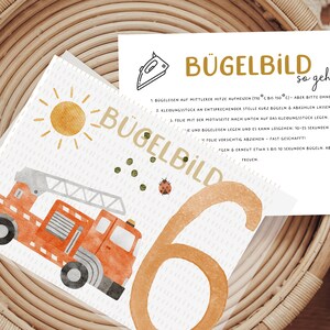 Könnte beinhalten: Eine weiße Karte mit Anweisungen zum Aufbügeln eines Feuerwehrauto-Designs. Die Karte trägt die Worte "Bügelbild" und "so geht's" in goldener Schrift. Die Karte liegt neben einer weißen Karte mit einer Aquarell-Illustration eines Feuerwehrautos, einer Sonne und der Zahl 6.
