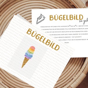 Könnte beinhalten: Anleitung zum Aufbügeln eines Bügelbildes auf Stoff. Die Anleitung ist in deutscher Sprache verfasst und enthält ein Bild eines Eisbechers mit Regenbogenstreuseln.