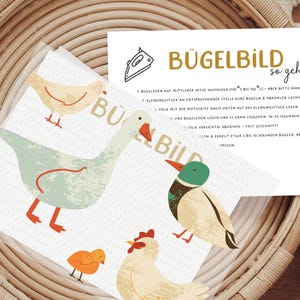 Könnte beinhalten: Eine weiße Karte mit Anweisungen zum Aufbügeln eines Bügelbildes. Die Karte hat einen gelben Titel, der "Bügelbild so geht's" lautet. Die Karte enthält auch Illustrationen von einer Ente, einer Gans, einem Huhn und einem Küken.