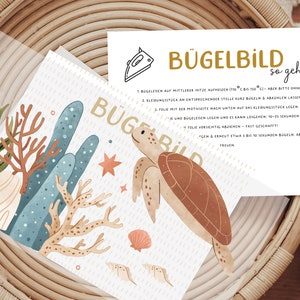 Könnte beinhalten: Eine weiße Karte mit einer braunen Schildkrötenillustration und Anweisungen zum Aufbügeln eines Stofftransfers. Der Text auf der Karte lautet "Bügelbild so geht's".