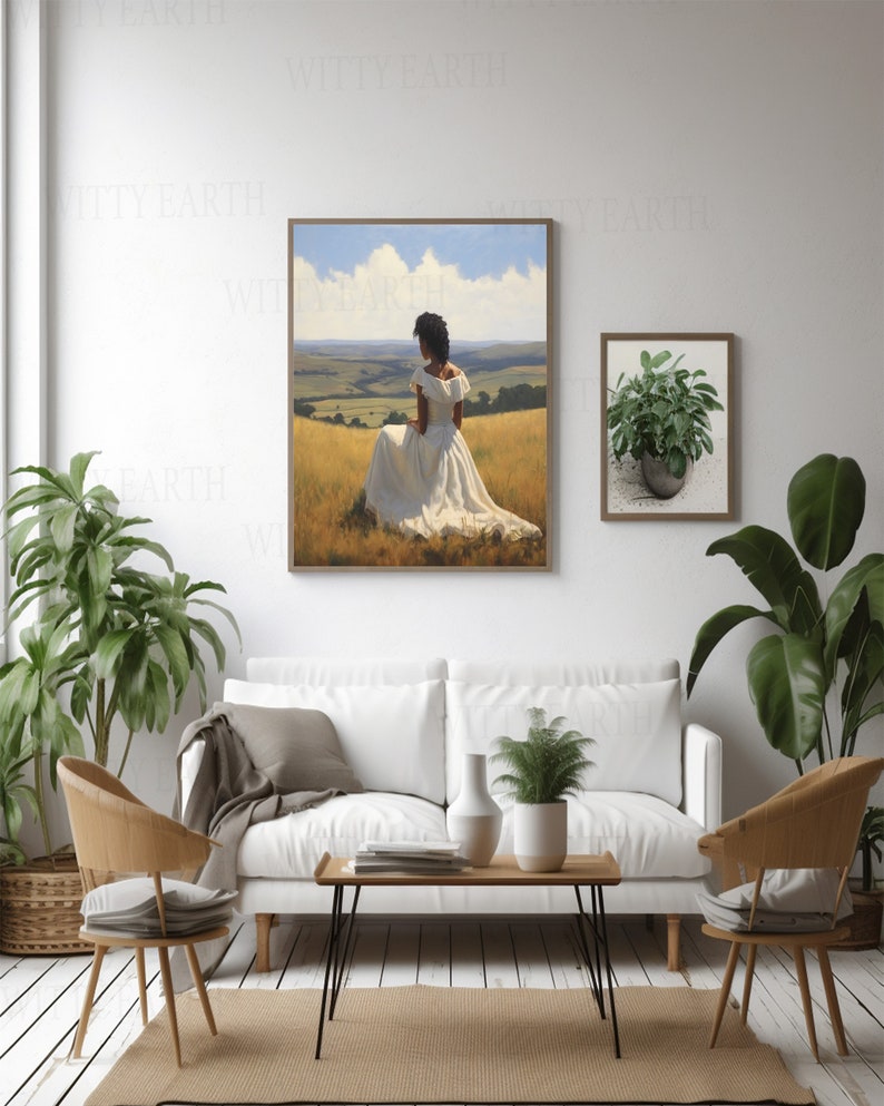 May include: A painting depicting a woman in a white dress seated in a field of long grass. The woman is facing away from the viewer, with her back to the camera. The painting is framed in a wooden frame and is hanging on a white wall.