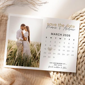May include: A wedding announcement card with a photo of a couple in a field. The text "save the date" is at the top, with the names "Marie & Andrew" and the date "MARCH 2026". A calendar highlights March 16th. The address is also included.