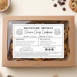 May include: A box of Signature Artisan Choco Chip Cookies with a label showing ingredients and contact information. The cookies are surrounded by chocolate chips, a small bowl of brown sugar, and a spoon.