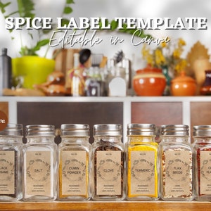 Pode incluir: Oito frascos de vidro para especiarias com etiquetas de papel castanho e texto preto. As etiquetas têm nomes diferentes para as especiarias, incluindo sésamo preto, sal, pó de cominho, cravo, açafrão, sementes de linho e flocos de pimenta. Os frascos estão dispostos em fila sobre uma superfície de madeira. O texto nas etiquetas diz "100% natural" e "Temperos".