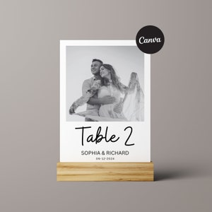 May include: Black and white photo of a couple on a table number card. The card is white with black text that says "Table 2", "Sophia & Richard", and "06-12-2024".