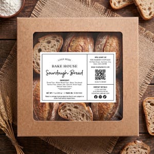 Puede incluir: Una caja de cartón marrón con una ventana transparente que muestra seis panes de masa madre. La etiqueta dice "BAKE HOUSE Sourdough Bread" y enumera los ingredientes. El peso neto es de 200 g.