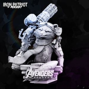 Könnte beinhalten: Eine graue 3D-gedruckte Figur von Rocket Raccoon aus dem Marvel Cinematic Universe. Rocket trägt einen grauen und schwarzen Iron Patriot-Anzug und einen Schal. Er hält eine große Waffe und hat eine kleine Groot-Figur auf seiner Schulter. Die Basis der Figur trägt die Aufschrift "Avengers Endgame".