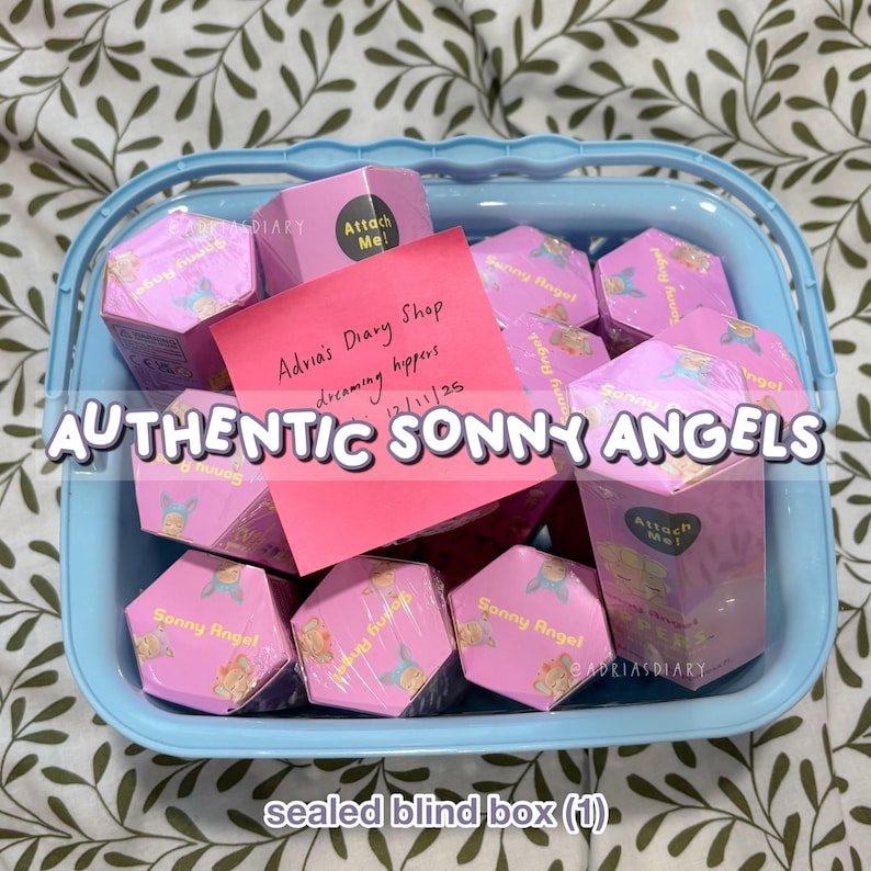 K&ouml;nnte beinhalten: Ein hellblauer Korb gef&uuml;llt mit rosa sechseckigen Boxen mit der Aufschrift "Sonny Angel". Ein pinkfarbener Haftzettel mit der Aufschrift "Advia's Diary Shop" und "dreaming hippers". Der Text "AUTHENTIC SONNY ANGELS" ist &uuml;berlagert. Versiegelte Blindboxen.