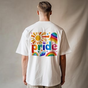 May include: A white short-sleeved t-shirt featuring a colourful graphic on the back. The design includes the word pride in multicoloured letters, surrounded by illustrations of a sun, a rainbow, stars, and abstract shapes in vibrant hues.