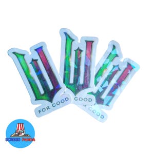 May include: A collection of holographic stickers with a stylized "W" design in green, red, and purple. Each sticker has the words "FOR GOOD" printed on it. The stickers are on a white background.