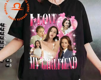 May include: Black t-shirt with a pink graphic that says "I LOVE MY GIRLFRIEND". The graphic features multiple images of a woman, pink hearts, and lightning bolts. The shirt has a crew neck and short sleeves.