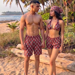 Op de afbeelding: Een bijpassende set van kastanjebruine shorts met een herhalend bloemenpatroon. De set bevat een halter-bikinitop en een bijpassende hoofddoek, beide gemaakt van dezelfde kastanjebruine stof met een kleine, lichtblauwe en witte bloemenprint.