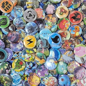 May include: A collection of colourful round buttons featuring various Pokemon characters and symbols. The buttons are made of plastic and have a glossy finish.