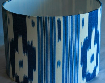 May include: A white and blue patterned lampshade with a cylindrical shape. The pattern features vertical stripes and a blue and white ikat design.