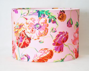 May include: A pink lampshade with a floral pattern featuring colourful poppies and butterflies. The lampshade is cylindrical and has a white background.