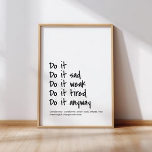 May include: A framed print with the words "Do it" followed by "Do it sad, Do it weak, Do it tired, Do it anyway" in black handwritten font. The bottom of the print reads "Consistency transforms small daily efforts into meaningful change over time."