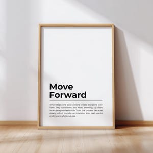 Pode incluir: Uma impressão emoldurada com as palavras "Move Forward" em negrito preto. Abaixo do título há um parágrafo de texto. A moldura é de cor de madeira clara e o fundo é branco. A impressão está encostada em uma parede branca.